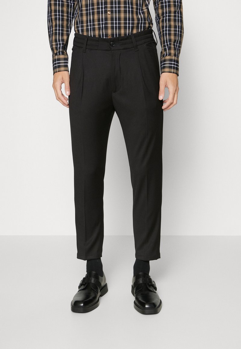 Zwarte op maat gemaakte broek met plooien, met een gladde textuur en een aansluitend ontwerp. Draag deze met zwarte nette schoenen en accentueer met een geruite blouse.