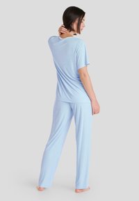 Conjunto de pijama azul claro confeccionado en tejido suave. Camiseta de manga corta con escote redondo y corte holgado; pantalones largos a juego con una silueta relajada.