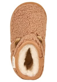 Brauner, gemütlicher Hausschuh mit einer strukturierten Fleece-Außenfläche und weicher, plüschiger Innenausstattung. Abgerundete Zehenform mit hellbraunen Akzenten und einem Etikett an der Seite.