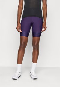 Lilla treningsshorts med en tettsittende design, laget av glatt, elastisk materiale. Har kontraststoff i kanten med et blomstermønster.