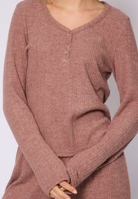 Top a maniche lunghe a coste color rosa polveroso con scollatura a V e tre bottoni. Texture morbida e design aderente con maniche lunghe.