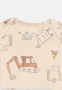 Beige rompertje met korte mouwen, bedrukt met een patroon van bouwvoertuigen, waaronder een bruine graafmachine en blauwe accenten, gemaakt van zachte katoen.