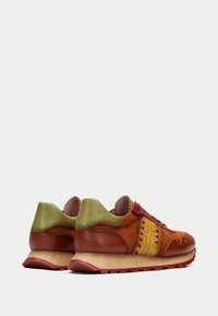 Sneaker in pelle e camoscio nei toni marrone, verde e bordeaux, con colletto scallop, dettagli testurizzati e suola rigata.