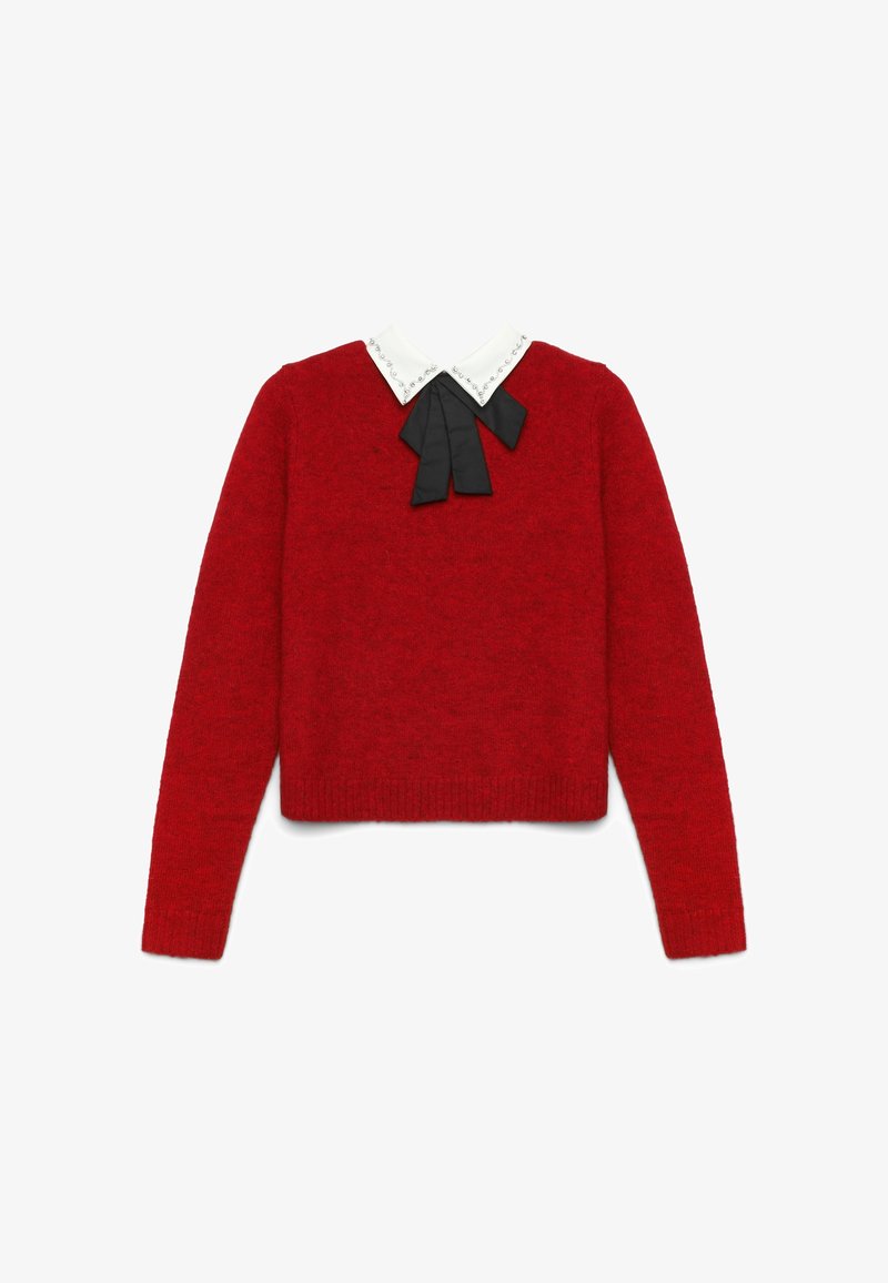 Maglione rosso con design corto, dotato di un colletto bianco e dettaglio in nastro nero. La texture appare morbida e a maglia.
