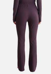 Lila ribbade leggings med en åtsittande midja. Tyget verkar mjukt och stretchigt, med en utsvängd bendesign och ingen synlig hårdvara.