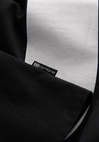 Mustavalkoinen kangas, jossa on pieni musta lappu, jossa lukee "ombre", ommeltuna saumaan.