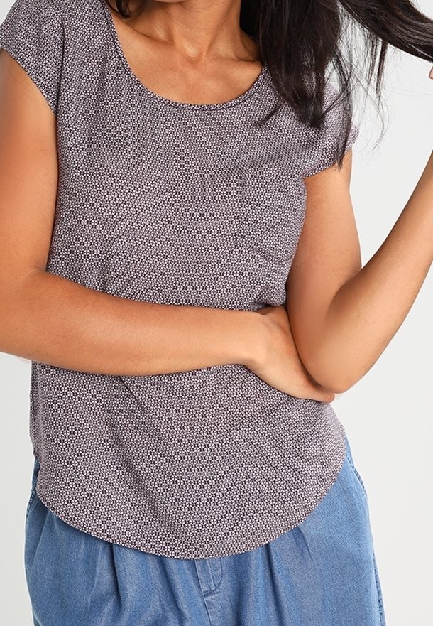 Kortärmad topp i marinblått med ett litet vitt geometriskt mönster, rundad halsringning och bröstficka; mjukt tyg och avslappnad passform.