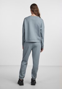 Felpa azzurra chiara e pantaloni jogger abbinati realizzati in tessuto morbido, con vestibilità oversize e polsini a costine, abbinati a sneaker nere testurizzate.
