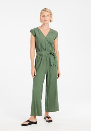 Green, textured jumpsuit with a V-neck, cap sleeves, and a tied waist. Features wide legs and is paired with black flip-flop sandals.