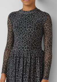 Langärmliges Kleid mit einem Schwarz-Grau-Leopardmuster. Transparenter, strukturierter Stoff mit einer gerafften Taille und glattem Halsausschnitt.