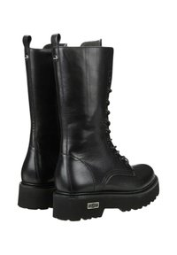 Stivali neri in pelle fino al ginocchio con laccio frontale, suola piatta in gomma e linguette laterali per la trazione. Presentano cuciture sollevate e un accento con marchio.