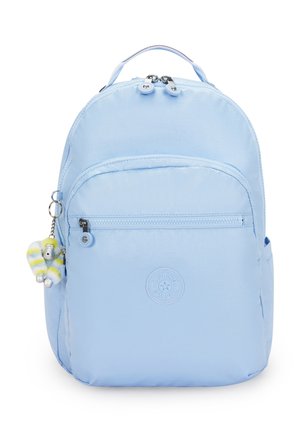 Sac à dos bleu clair avec poche zippée à l'avant, poignée supérieure, poche latérale et un petit porte-clés singe duveteux attaché au curseur de la fermeture éclair.