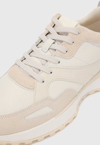 Baskets en beige et crème avec une tige en cuir texturé, des accents en suède, un design à lacets et une semelle extérieure blanche épaisse. Marquage sur la languette.