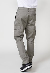 Pantalones cargo grises con múltiples bolsillos laterales, corte recto, fabricados con un tejido ligero, terminados con una textura suave y costuras reforzadas.