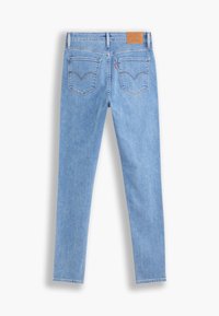 Jean en denim bleu clair vu de dos avec deux poches arrière, un patch de marque en cuir marron et une coupe slim droite.