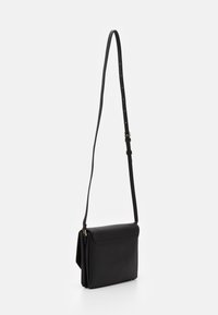 Borsa a tracolla in pelle nera con un design elegante, caratterizzata da un cappuccio pieghevole, una tracolla regolabile e dettagli in metallo dorato.