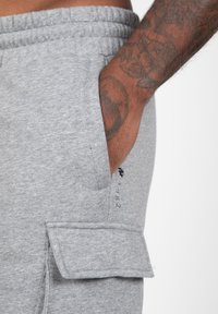 Grijze katoenen sweatpants met een elastische tailleband en zijzak, met een cargovlapzak en bedrukte details op het been.