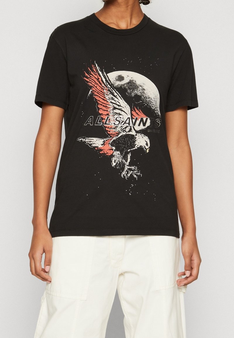 Svart bomull t-shirt med en grafisk bild av en flygande örn, röda och vita detaljer, samt texten "ALLSAINTS" nedan. Korta ärmar och rundad halsringning.