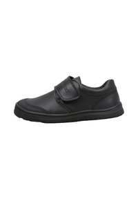 Zapato de cuero negro con punta redondeada, correa de Velcro ajustable y suela de goma texturizada para mayor agarre. Presenta detalles cosidos a lo largo de los bordes.