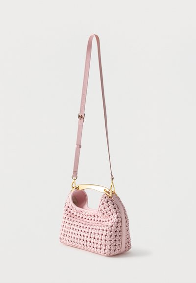 Ροζ πλεκτή δερμάτινη τσάντα χειρός με χρυσή λαβή και ρυθμιζόμενο ιμάντα ώμου πάνω σε λευκό απλό φόντο.