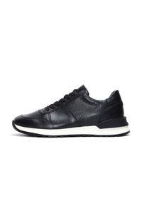 Zapatilla negra de cuero con parte superior texturizada, cordones planos y una media suela blanca. Presenta una puntera redondeada y un talón reforzado para mayor durabilidad.