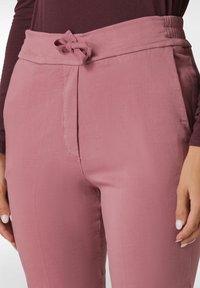 Rosa bomuldsblandingsbukser med en glat tekstur, der har en bundet sløjfeaccent i taljen og en tætsiddende silhuet.