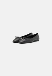 Ballerine in pelle nera con punta arrotondata, caratterizzate da un’accento a fiocco e un piccolo dettaglio metallico sulla parte anteriore. Suola piatta e texture liscia.