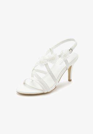 White strappy high-heeled sandal with floral embellishments and a buckle ankle strap, featuring a mid-height stiletto heel.
