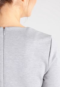 Abito grigio con texture e zip sul retro, caratterizzato da una scollatura dritta e maniche corte, che evidenzia un design minimalista.