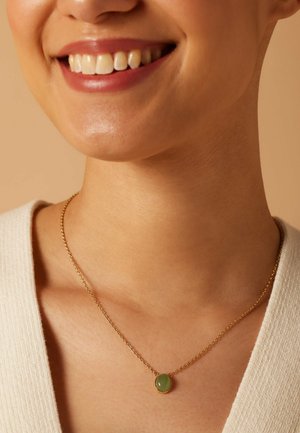 Collier en chaîne dorée avec un pendentif en pierre précieuse verte ronde. La chaîne est délicate, avec une texture lisse.