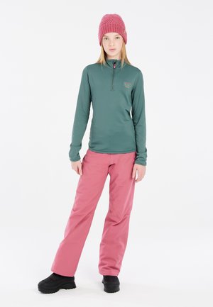 T-shirt thermique à manches longues, vert, avec un col zippé mi-hauteur ; pantalon de neige rose, résistant à l'eau ; bottes d'hiver noires et texturées ; bonnet en tricot rose.