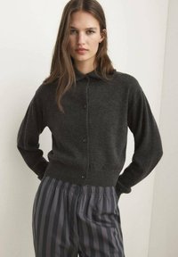 Dark gray knit cardigan with a button-up front and a classic collar, paired with gray striped trousers featuring an elastic waistband.