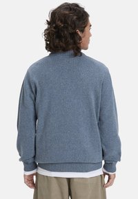 Helles blaues, gestricktes Sweatshirt mit hohem Kragen, gerippten Bündchen und Saum. Besitzt eine strukturierte Oberfläche mit Sprenkeln in helleren Farbtönen.