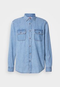 Svetlo modra denim srajca z dolgimi rokavi, zapenjanjem na gumbe spredaj, dvema prsnikoma žepoma in ovratnikom. Poudarjeno je z kontrastnim šivanjem in kovinskimi gumbi.