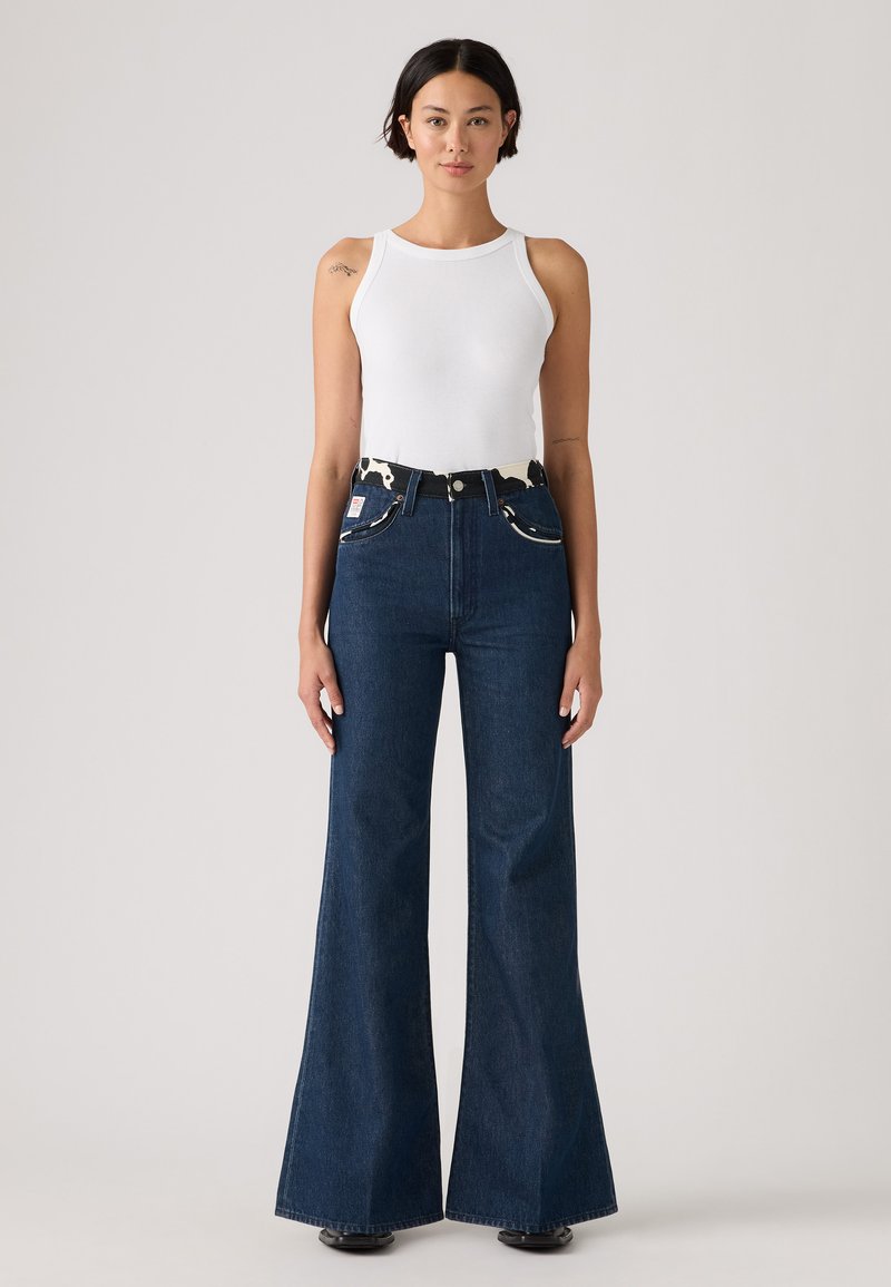 Høj talje flared jeans i mørk denim, med et sort og kuadmønstret bælte, fem lommer og et klassisk snit. Glat tekstur.