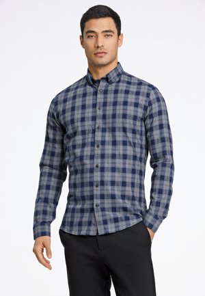 Chemise à carreaux bleu marine et gris avec des manches longues, fabriquée dans un tissu doux, dotée d'un col classique et de boutons foncés.