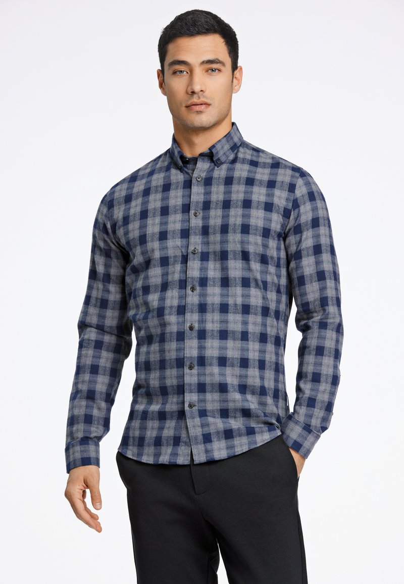 Camisa de cuadros en tonos azul marino y gris, con botones y mangas largas, fabricada en un tejido suave, que presenta un cuello clásico y botones oscuros.