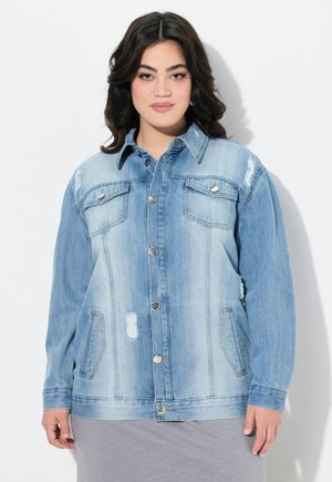 Chaqueta de denim azul claro con un frente abotonado, dos bolsillos en el pecho y detalles desgastados. Presenta un collar extendido y mangas con puños.