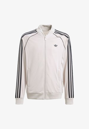 Světlá šedá bunda na zip s černými pruhy na rukávech, žebrovanými manžetami a límečkem. Má boční kapsy a malé logo na hrudi.