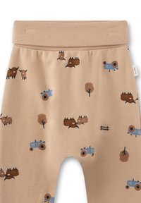 Beige Leggings mit einem verspielten Bauernhofthema, verziert mit blauen Traktoren, braunen Tieren und Bäumen, aus weichem Baumwollstoff mit einem elastischen Bund.