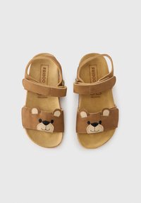 Καφέ δερμάτινα σανδάλια με σχέδιο προσώπου αρκούδας στα λουριά, ρυθμιζόμενες πόρπες και μαλακή σουέτ εσωτερική σόλα. Ελαφριά και ανοιχτά στα δάχτυλα.