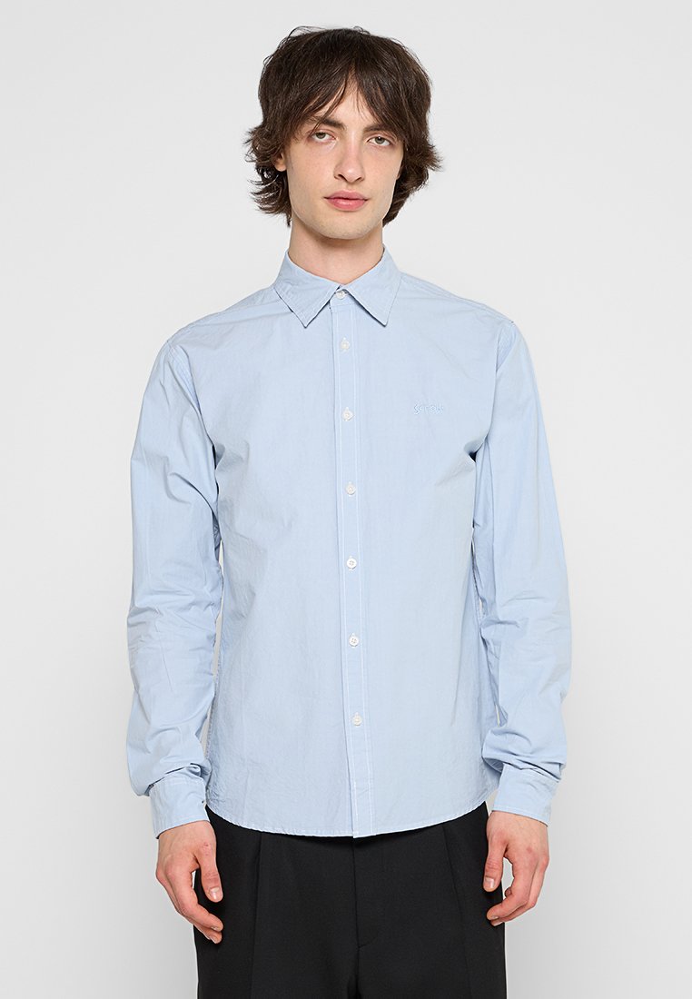 Camicia a maniche lunghe azzurro chiaro con colletto a punta, chiusura con bottoni e ricamo del logo discreto. Tessuto di cotone liscio.