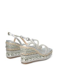 Wedge sandalen in zilver, met gevlochten jute-details, kralenaccenten en meerdere verstelbare bandjes met een gladde ondergrond.