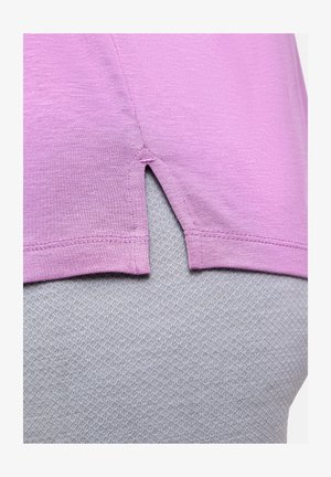 Paarse, lichtgewicht stoffen blouse met een zijsplitdetail, gedragen over een gestructureerd grijs kledingstuk met een diamantpatroon.