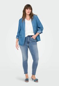 Šviesiai mėlynas džinsinis švarkas su pasuktomis rankovėmis, derinamas su baltu nėriniuotu marškinėliu ir mėlynomis džinsinėmis kelnėmis, papildytas mėlynais aukštakulniais sandalais su gėlių akcentais.