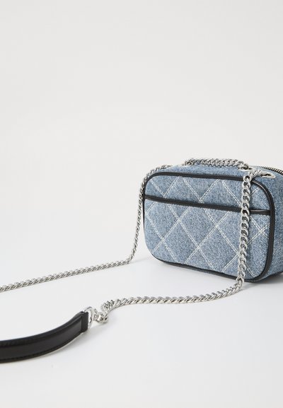 Denim crossbody bag with quilted pattern, silver chain strap, black trim, and rectangular shape. Features compact size and smooth texture.