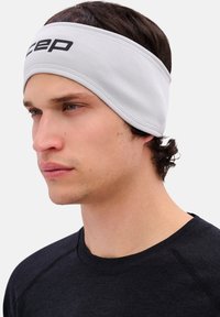 Grijs sportief hoofdband met een gestructureerde stof en een zwart logo. Het zit strak rond het voorhoofd en is geschikt voor sportactiviteiten.