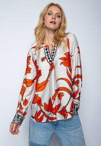 Bluzka z długim rękawem z lekkiego satenu, w żywych pomarańczowych wzorach kwiatowych na białym tle. Czarne haftowane akcenty przy dekolcie i mankietach.