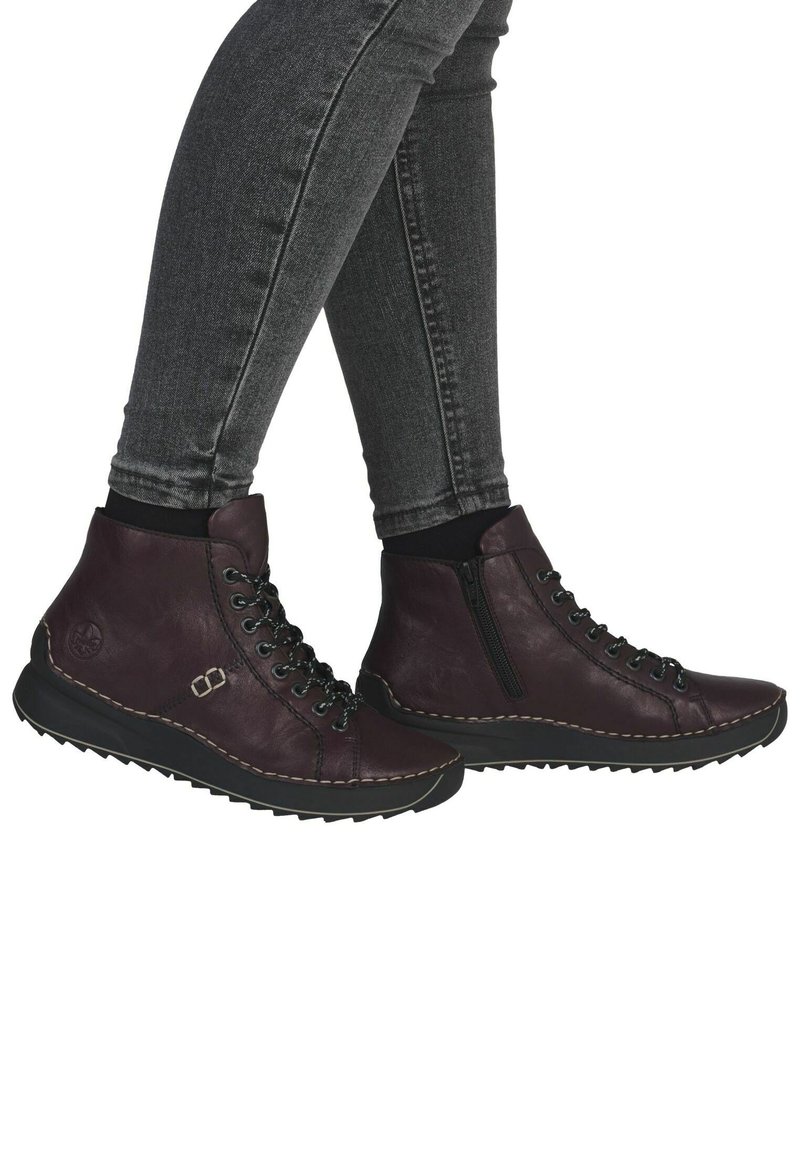 Bottes chelsea violettes en cuir, avec une fermeture éclair et un laçage sur le devant, des surpiqûres et une semelle en caoutchouc noir texturé.
