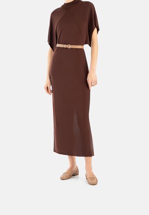 Brown maxi dress with short sleeves and a high neck, featuring a beige belt; paired with light-colored, perforated loafers.